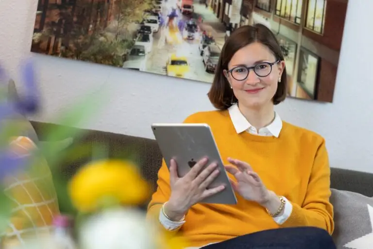 Hörgeräte mit Handy verbinden – Frau steuert ihre Hörgeräte per App auf dem Tablet