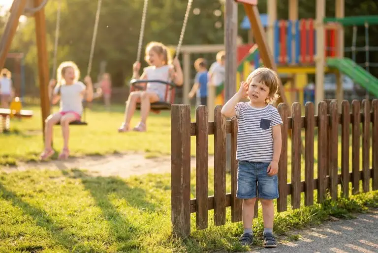Kind auf dem Spielplatz hält sich das Ohr – mögliches Anzeichen für Schwerhörigkeit bei Kindern